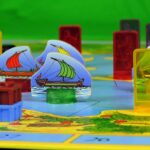"Boat" image by Gianni Crestani (Pixabay) showing a gameboard on which colorful plastic pieces are positioned, including translucent pieces with images of soldiers on them, and other pieces showing images of ancient trireme ships.