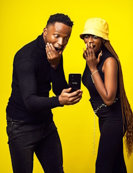 Couple looking at cell phone in surprise (gold background)