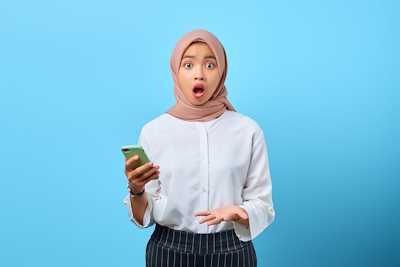 Girl looking at cell phone in surprise (blue background)